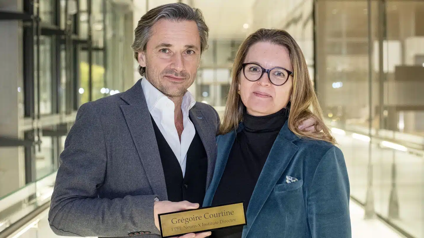 Two people holding a plaque in a hallway